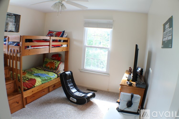 A room with a bunk bed, a chair, and a television.