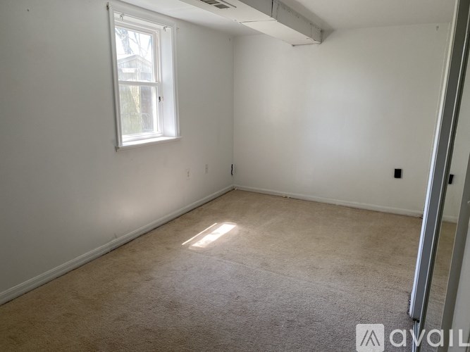 A room with a window and carpeted floor.