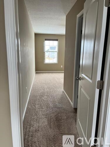 A hallway with a carpeted floor and white walls.