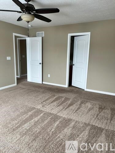 A room with a ceiling fan and two doors.