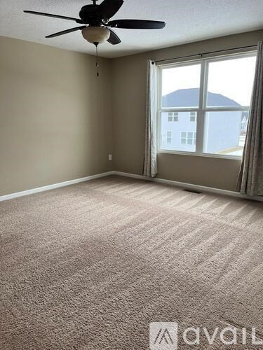 A room with a carpeted floor and a ceiling fan.