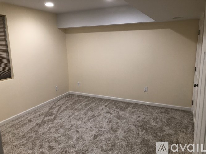 A room with a carpeted floor and a window with blinds.