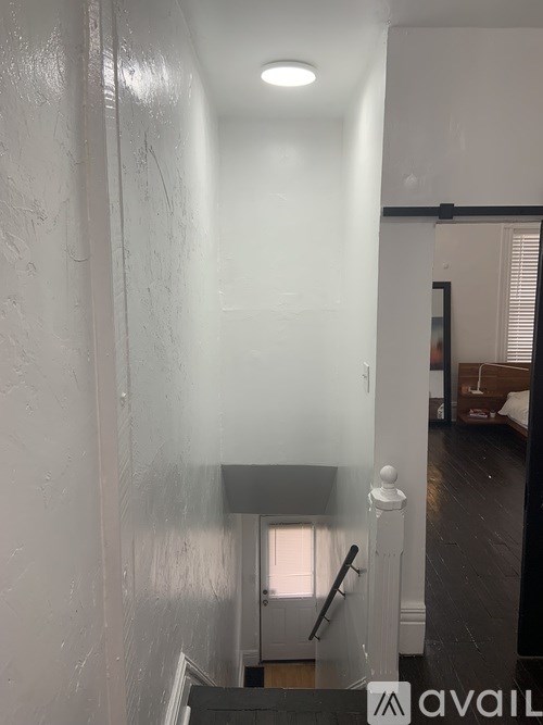 A hallway with a light on the ceiling and a door on the right.