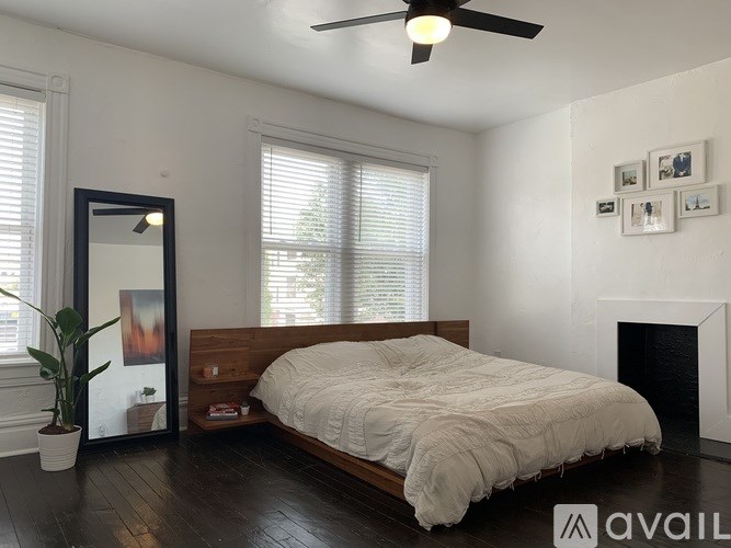 A bedroom with a bed, a plant, a mirror, and a fireplace.