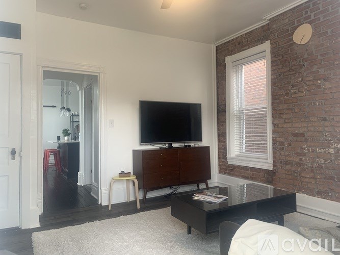 A living room with a brick wall and a flat screen TV.