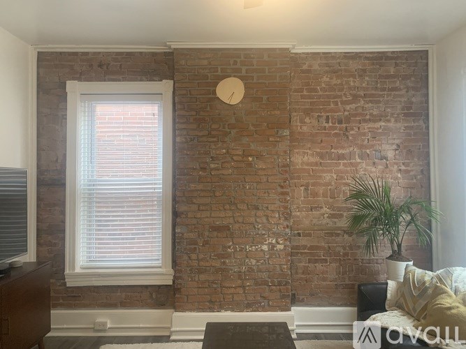 A room with a brick wall and a window with blinds.