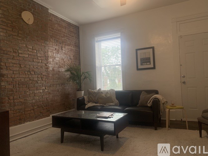 A living room with a brick wall and a black couch.