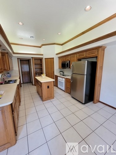 A kitchen with a refrigerator, sink, and cabinets.