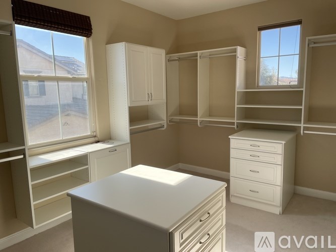 A room with a desk, drawers, and shelves.