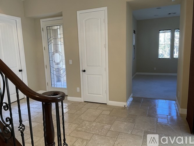 A hallway with a tiled floor and a wooden staircase.