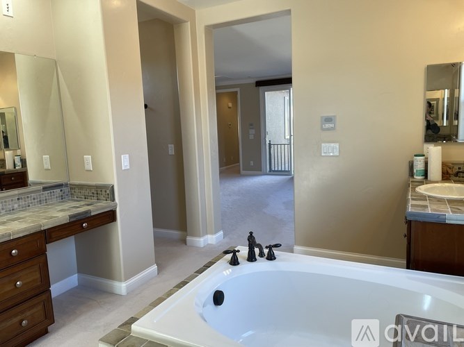 A bathroom with a tub, sink, and mirror.