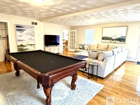 A pool table in a room with a couch and a television.
