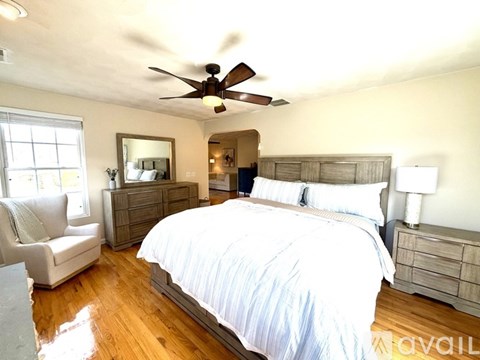 A bedroom with a large bed and a ceiling fan.