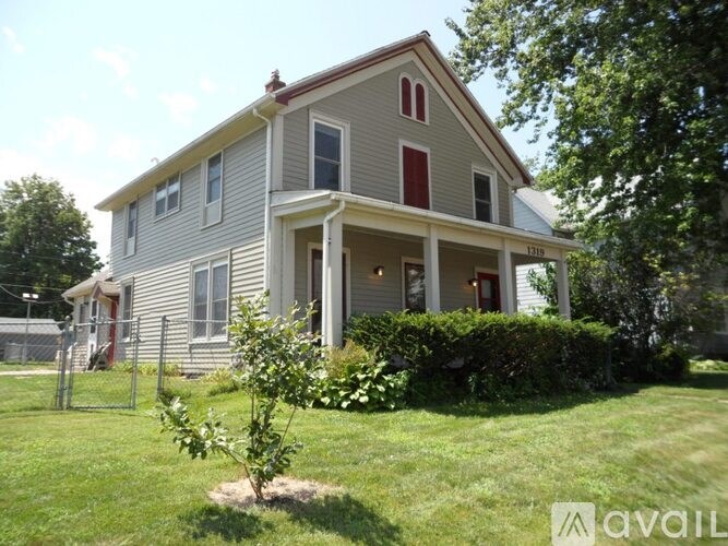 A house with a red door and a tree in front of it.