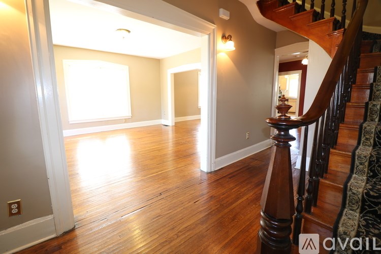 A wooden staircase with a carpeted runner leads up to a second floor landing.