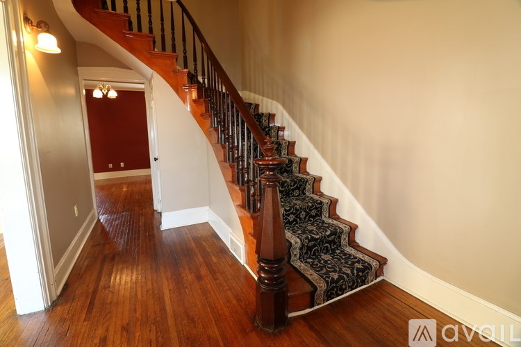 A wooden staircase with a black carpeted runner.