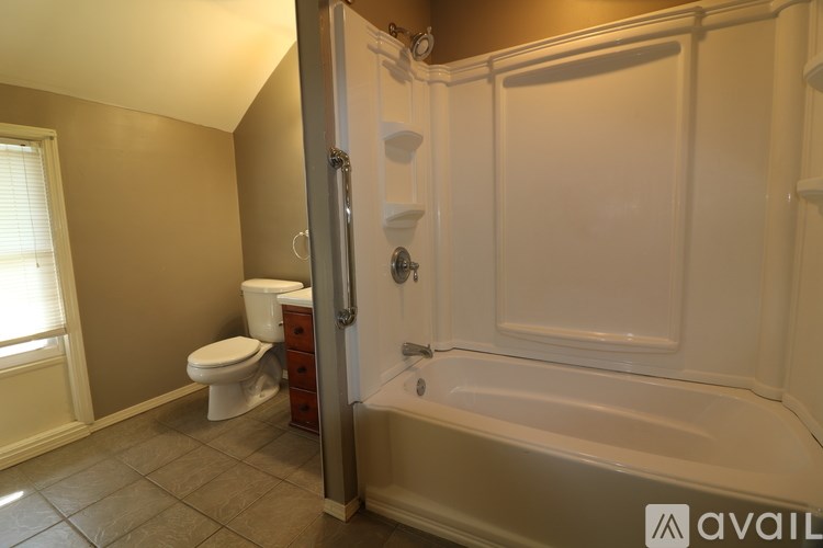 A bathroom with a toilet, tub, and window.