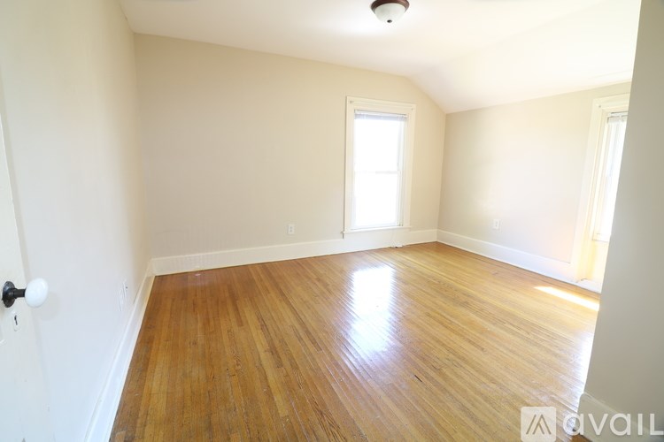A room with wooden flooring and a window letting in natural light.