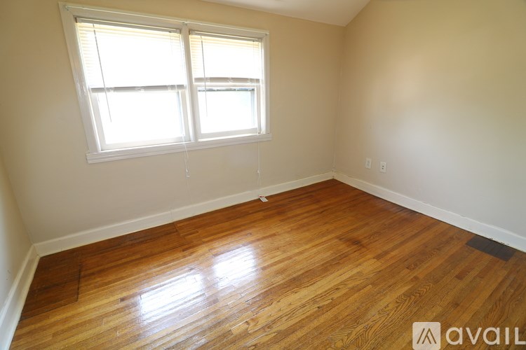 A room with wooden flooring and a window letting in sunlight.