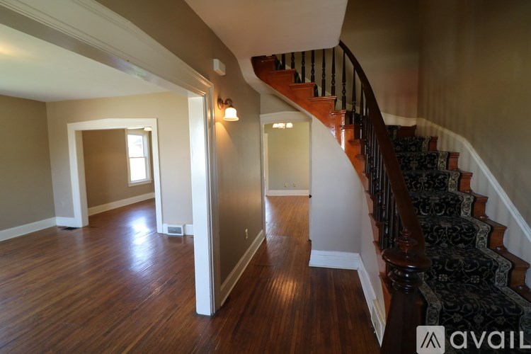 A wooden staircase with a black and white carpeted runner.