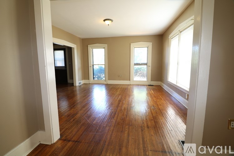 A room with wooden floors and a window on the right side.