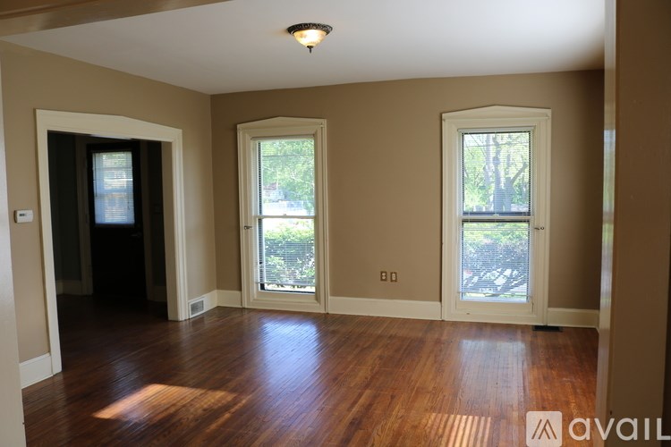A room with wooden floors and three windows.