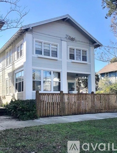 A two-story house with a wooden fence in front.