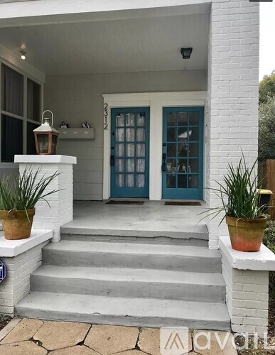 A white house with a blue door and steps leading to it.