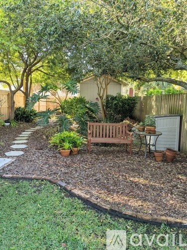 A backyard with a bench, a table, and a tree.