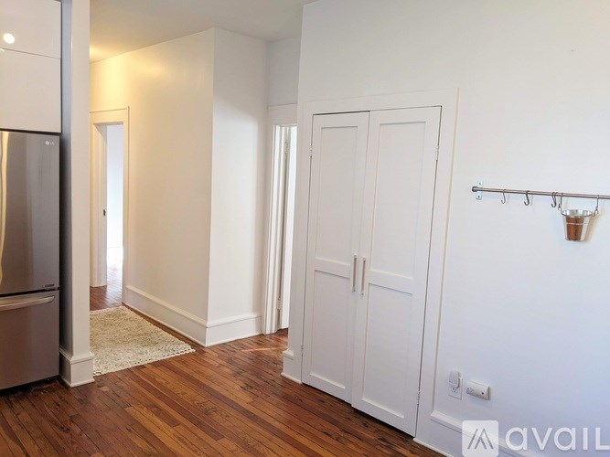 A kitchen with a refrigerator and wooden floors.