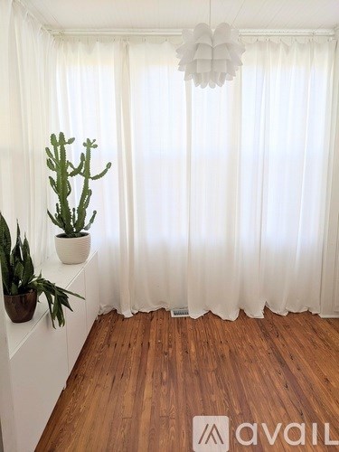 A room with a white curtain and a wooden floor.