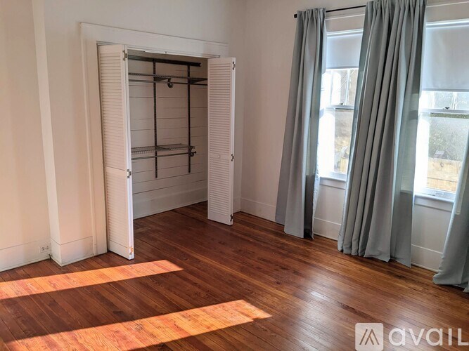 A room with a wooden floor and a white door with a shelf inside.