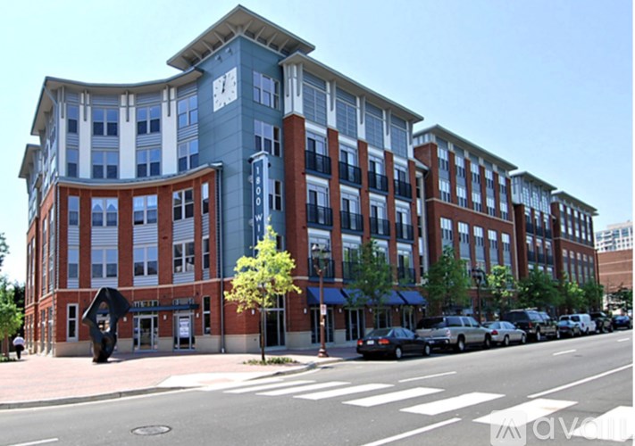 A street view of a multi-story building with a parking lot in front.