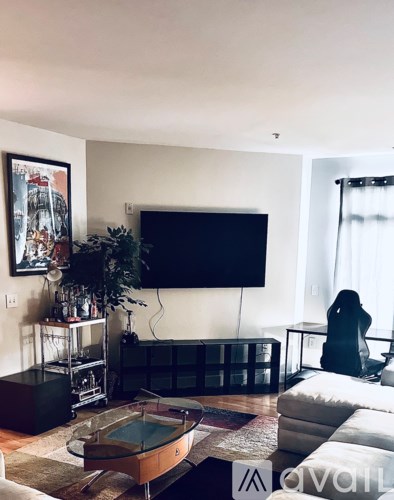 A woman is sitting on a couch in a living room with a flat screen TV mounted on the wall.