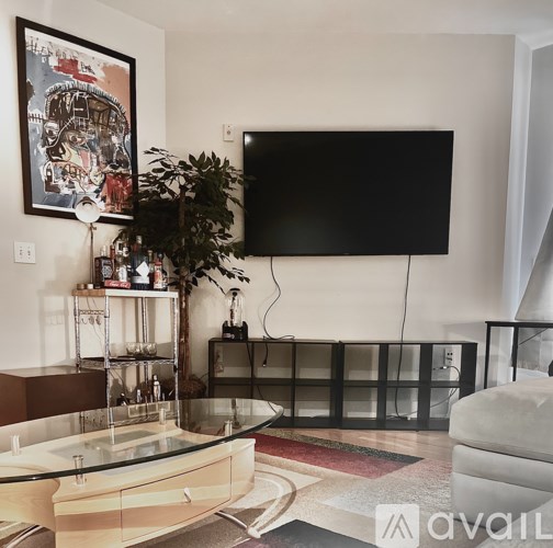 A living room with a glass table and a flat screen TV mounted on the wall.
