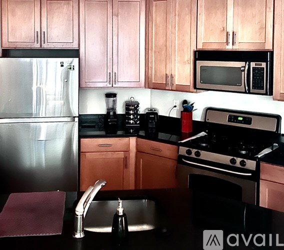A kitchen with a refrigerator, microwave, oven, and sink.