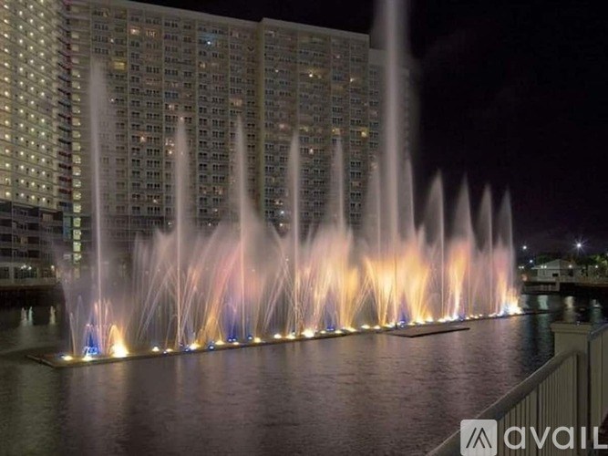 A large fountain in front of a building at night.