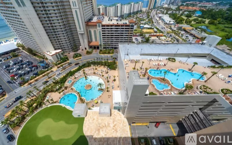 A large building with a pool in the middle of a green area.