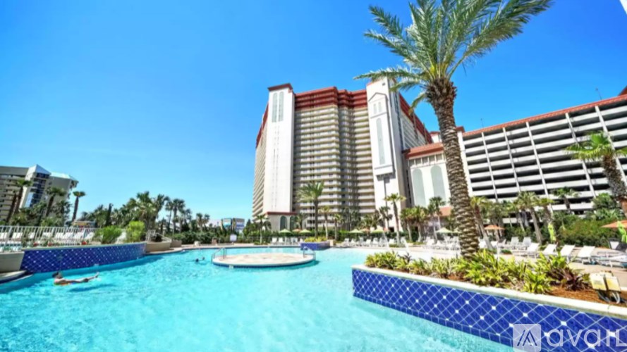 A large hotel with a pool in front of it.