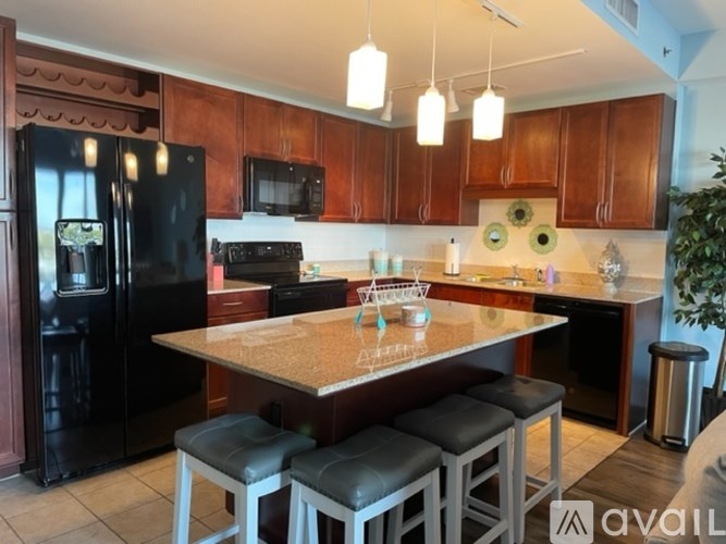 A kitchen with a black fridge, black stools and a wooden table.