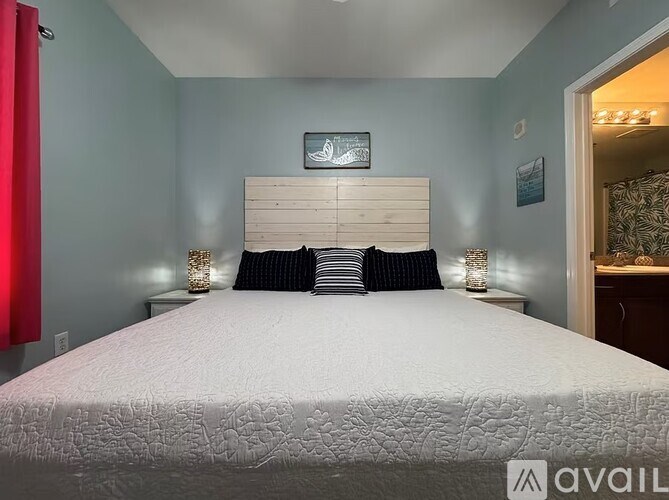 A bed with a white comforter and a wooden headboard with a picture above it.