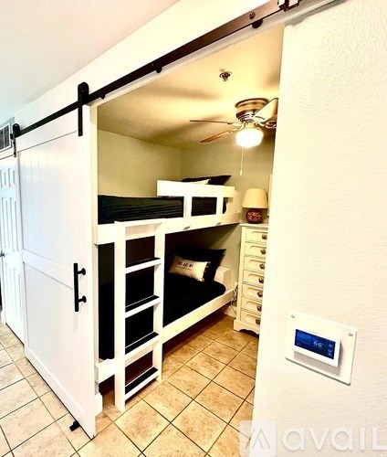 A small room with a bunk bed and a fan.