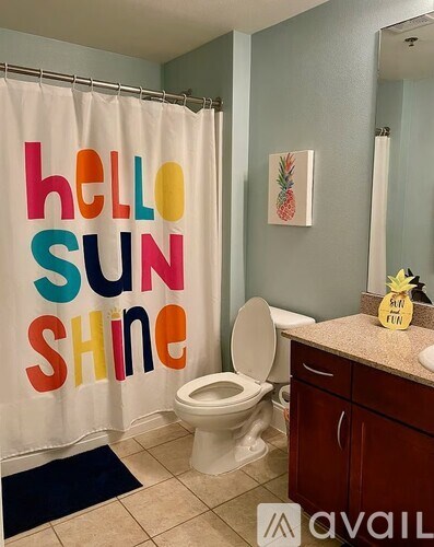 A bathroom with a shower curtain that says "hello sun shine".