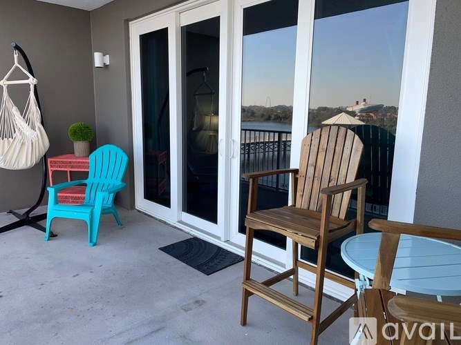 A balcony with a hanging chair, a blue chair, a wooden chair, and a table.
