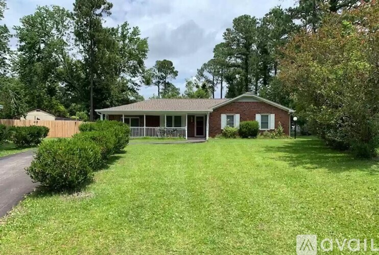 A house with a green lawn and trees in the background.