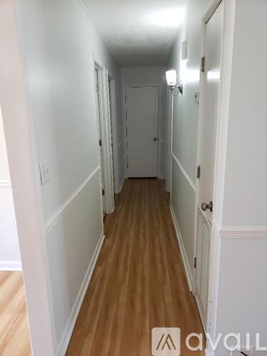 A long hallway with wood floors and white walls.