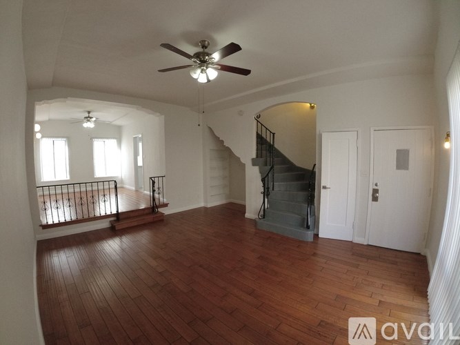 A spacious room with wooden floors and a staircase.