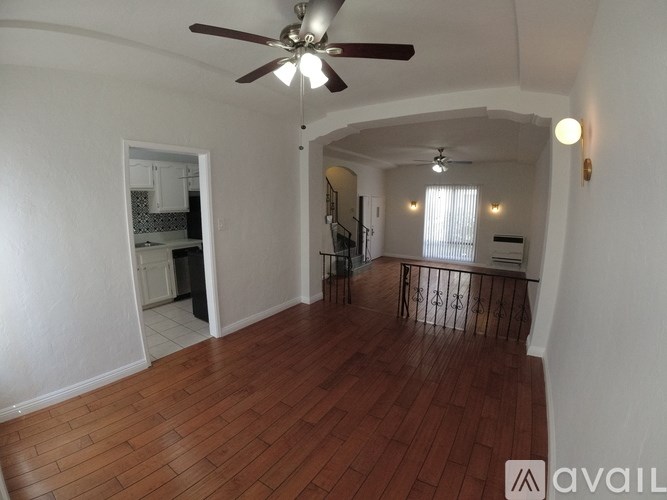 A room with a ceiling fan and wooden flooring.