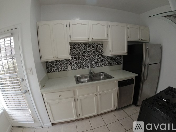 A kitchen with white cabinets and a black and white backsplash.