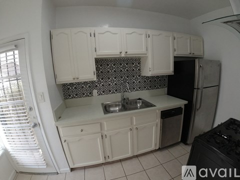 A kitchen with white cabinets and a black and white backsplash.